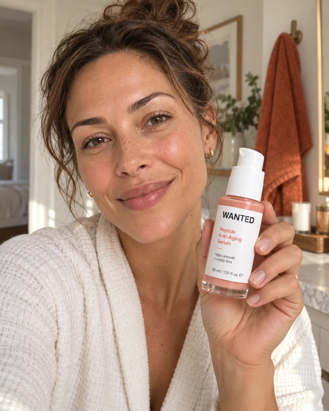 Hanna in a robe holding the WANTED serum at her bathroom sink